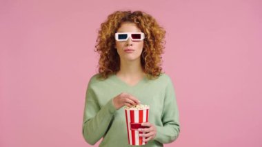 3D gözlüklü pozitif kadın pembe üzerine izole edilmiş patlamış mısır yiyor.