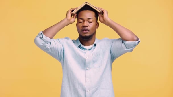 Bored African American Man Holding Book Head Isolated Yellow — Stock Video