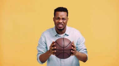Üzgün Afrikalı Amerikalı bir adam, sarı alanda izole edilmiş basketbol maçı izliyor.