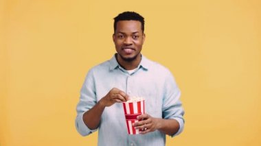 Gülümseyen Afro-Amerikan adam sarı üzerine izlenmiş bir film izliyor.