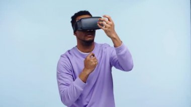 VR kulaklıklı Afro-Amerikan adam mavi alanda izole edildi.