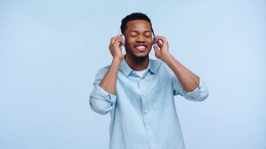 Mavi kulaklıklı Afro-Amerikan adam tek başına dans ediyor.