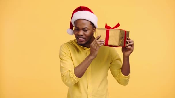 Curious African American Man Shaking Gift Box Isolated Yellow — Stock Video