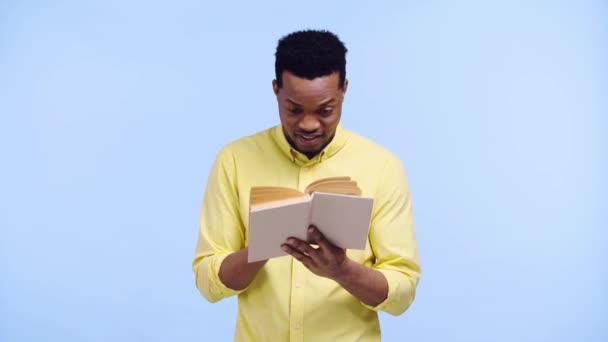 Smiling African American Man Reading Book Isolated Blue — Stock Video