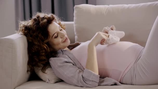 Happy Pregnant Woman Lying Sofa Baby Shoes — Stok video