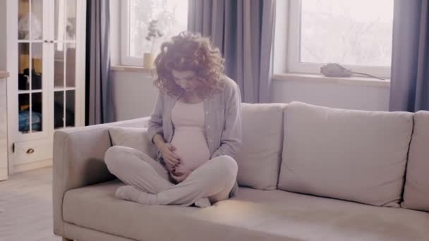 Glücklich Schwangere Frau Streichelt Bauch Auf Sofa Lotus Pose — Stockvideo