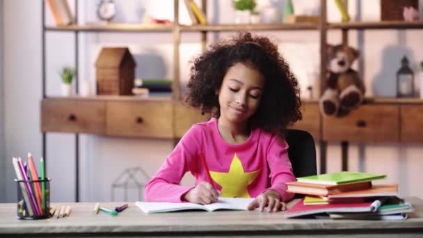 Leende Afrikanskt Amerikanskt Barn Gör Läxor Och Viftar Med Handen — Stockvideo