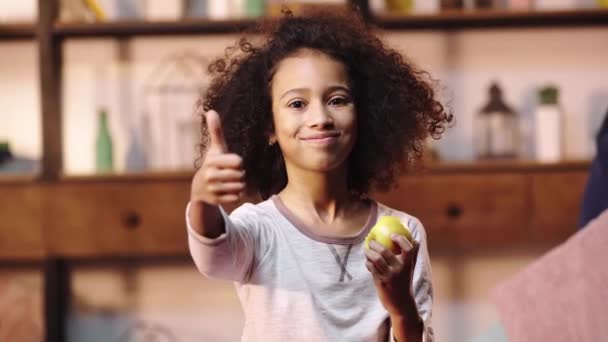 Afro Amerikai Gyerek Mutogatja Hüvelykujját Miközben Almát Eszik — Stock videók