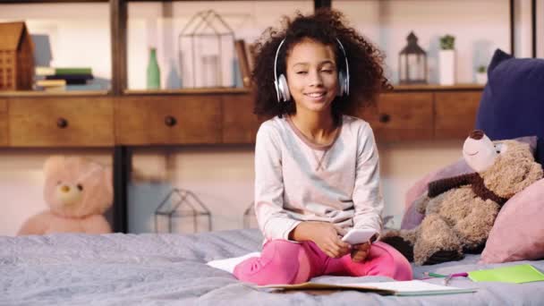 African American Child Listening Music While Doing Homework Bed — Stock Video