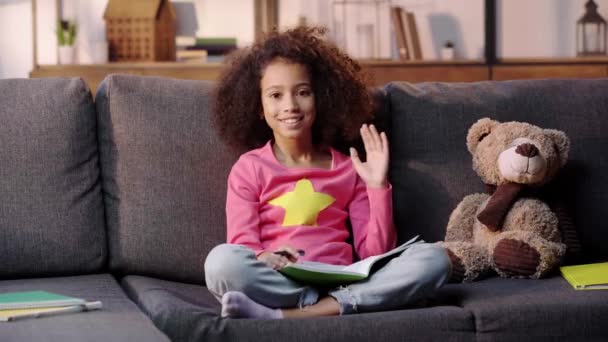 Smiling African American Child Waving Hand While Doing Homework Sofa — ストック動画