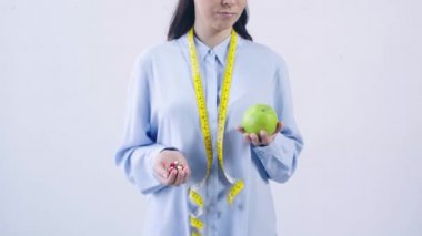 Beyaz üzerinde izole edilmiş vitamin ve elma karşılaştıran kadın manzarası.