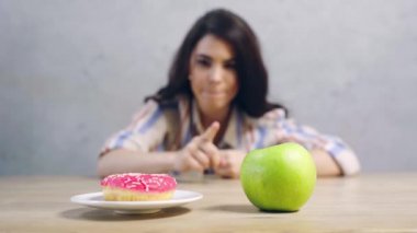Elma ve çörek arasında seçim yapan bir kadın. 