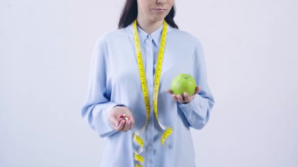 Beskärd Bild Kvinna Jämföra Vitaminer Och Äpple Isolerad Vitt — Stockvideo