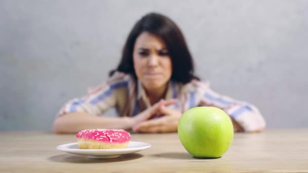 苹果和甜甜圈对困惑女孩的选择性聚焦 — 图库视频影像