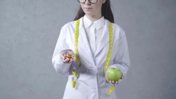 Καλλιεργημένη Άποψη Του Γιατρού Επιλέγοντας Μεταξύ Μήλου Και Βιταμινών Γκρι — Αρχείο Βίντεο