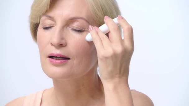 Dojrzała Kobieta Stosująca Wałek Oczu Izolowany Biało — Wideo stockowe