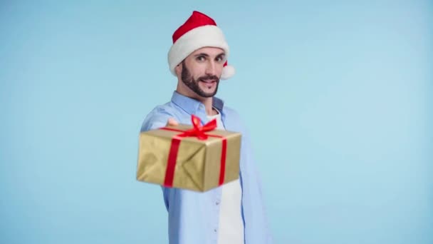 Fokuszug Eines Mannes Mit Weihnachtsmütze Und Geschenk Isoliert Auf Blau — Stockvideo