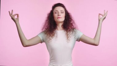 Rahat bir kadın pembe üzerine izole edilmiş meditasyon yapıyor. 