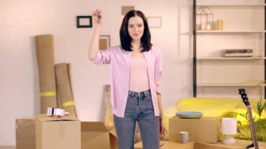Smiling woman showing keys at camera in new home