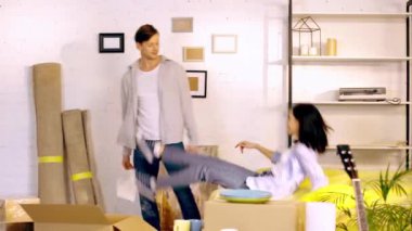 Couple dancing and fooling around near boxes in new home