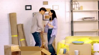 Young couple dancing near boxes in new home