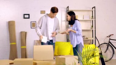 Young couple packing books in boxes in living room