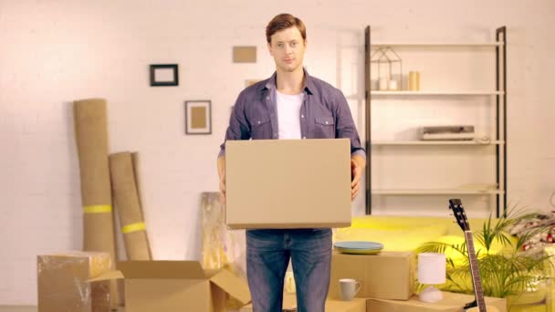 Hombre Joven Poniendo Caja Cartón Nuevo Hogar — Vídeo de stock