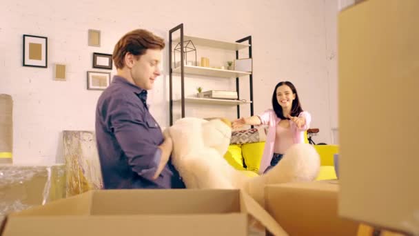 Mann Nimmt Teddybär Aus Paket Und Gibt Freundin Auf Couch — Stockvideo