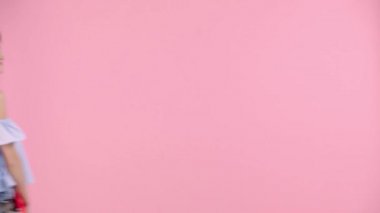 Çekici, neşeli kızlar kaykay tutarken pembe poz veriyorlar.