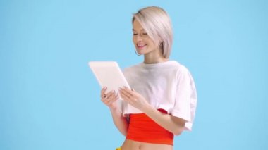 Mavi ekranda yeşil ekranlı dijital tablet gösteren gülümseyen kız