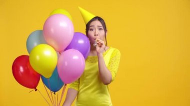 Balon şişiren Asyalı kız sarı renkte izole edilmiş. 
