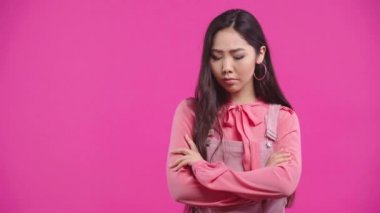 Üzgün Kazak kız kollarını kavuşturmuş pembe üzerinde tek başına duruyor. 