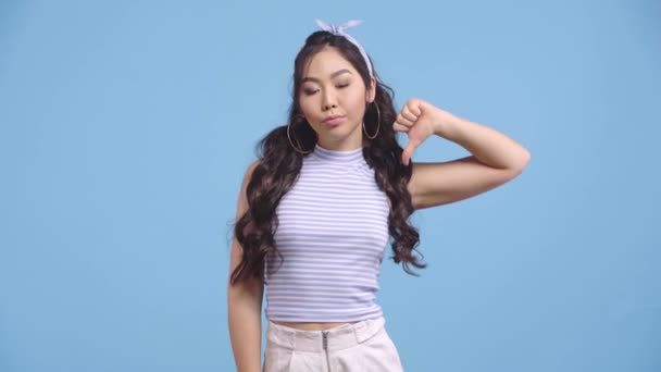 Hoşnutsuz Asyalı Kadın Mavi Üzerine Izole Edilmiş Baş Parmağını Gösteriyor — Stok video