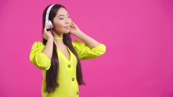 幸せなカザフスタンの女の子ピンクで隔離された音楽を聞いて — ストック動画