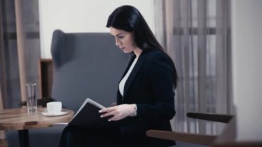 İş kadını belgelerle çalışıyor ve restoranda kahve içiyor. 