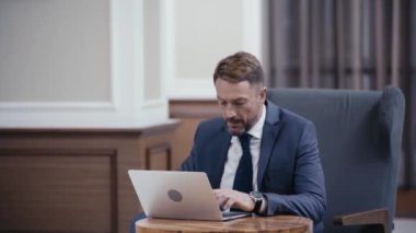 Restoranın lobisinde dizüstü bilgisayar kullanan bir iş adamı.