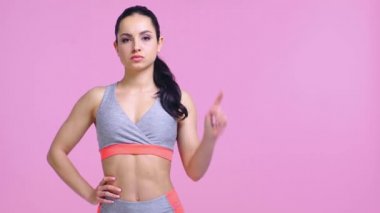 Tatminsiz sporcu kadın pembe üzerine izole edilmiş baş parmağını gösteriyor.