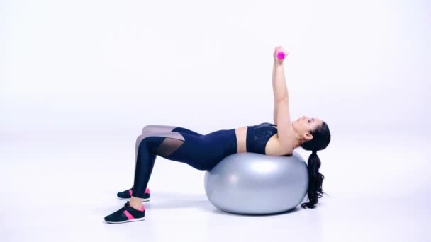 Mädchen Auf Fitnessball Trainiert Mit Kurzhanteln Auf Weiß — Stockvideo