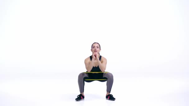 fille sportive avec des élastiques faire squats isolé sur blanc  