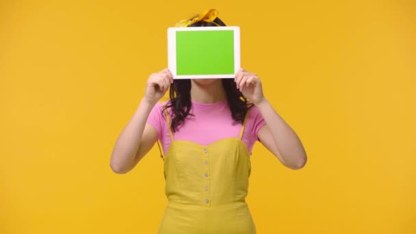 Mulher Cobrindo Rosto Com Tablet Digital Sorrindo Isolado Amarelo — Vídeo de Stock