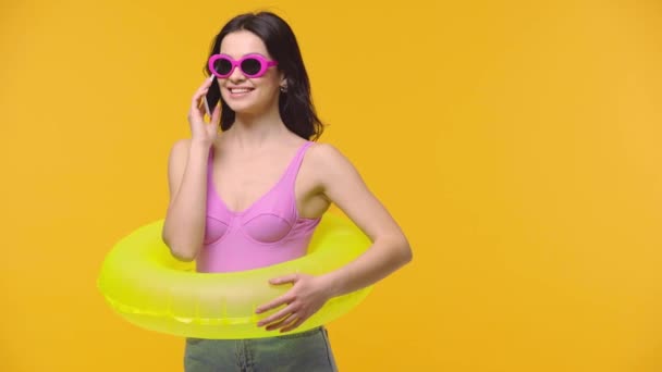 黄色に隔離されたスマートフォンで話すインフレータブルリングを持つ女性 — ストック動画