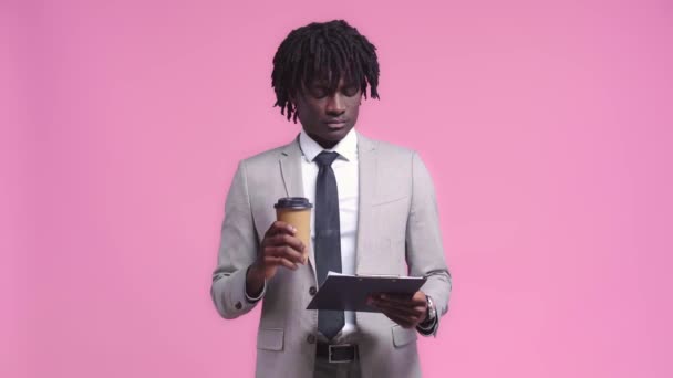 ピンクに隔離された契約コーヒーを飲むアフリカ系アメリカ人ビジネスマン — ストック動画