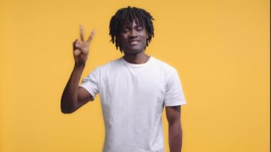 Afro-amerikan adam gülümsüyor ve zafer işareti gösteriyor.