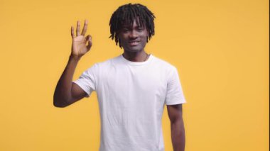 Afro-amerikan adam iyi işareti gösteriyor. Sarı üzerine izole edilmiş.