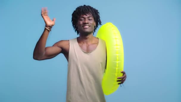 African American Man Passing Swim Ring Waving Hand Isolated Blue — Stock Video