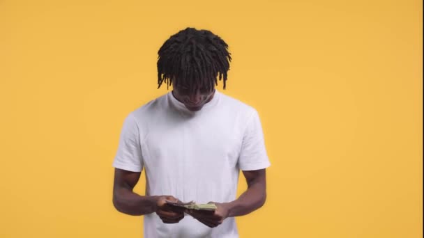 アフリカ系アメリカ人男性会計と黄色に隔離されたお金を示す — ストック動画