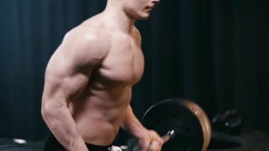 Spor salonunda halter kaldıran kaslı adamın kırpılmış görüntüsü. 