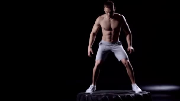 Muskulöser Mann Springt Auf Autoreifen Auf Schwarz — Stockvideo
