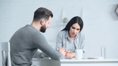 Üzgün bir adam evde hoşnutsuz bir kadınla konuşuyor. 