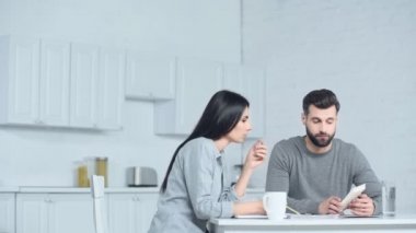 Kadın, üzgün adamın yakınındaki hesap makinesini işaret ediyor. 